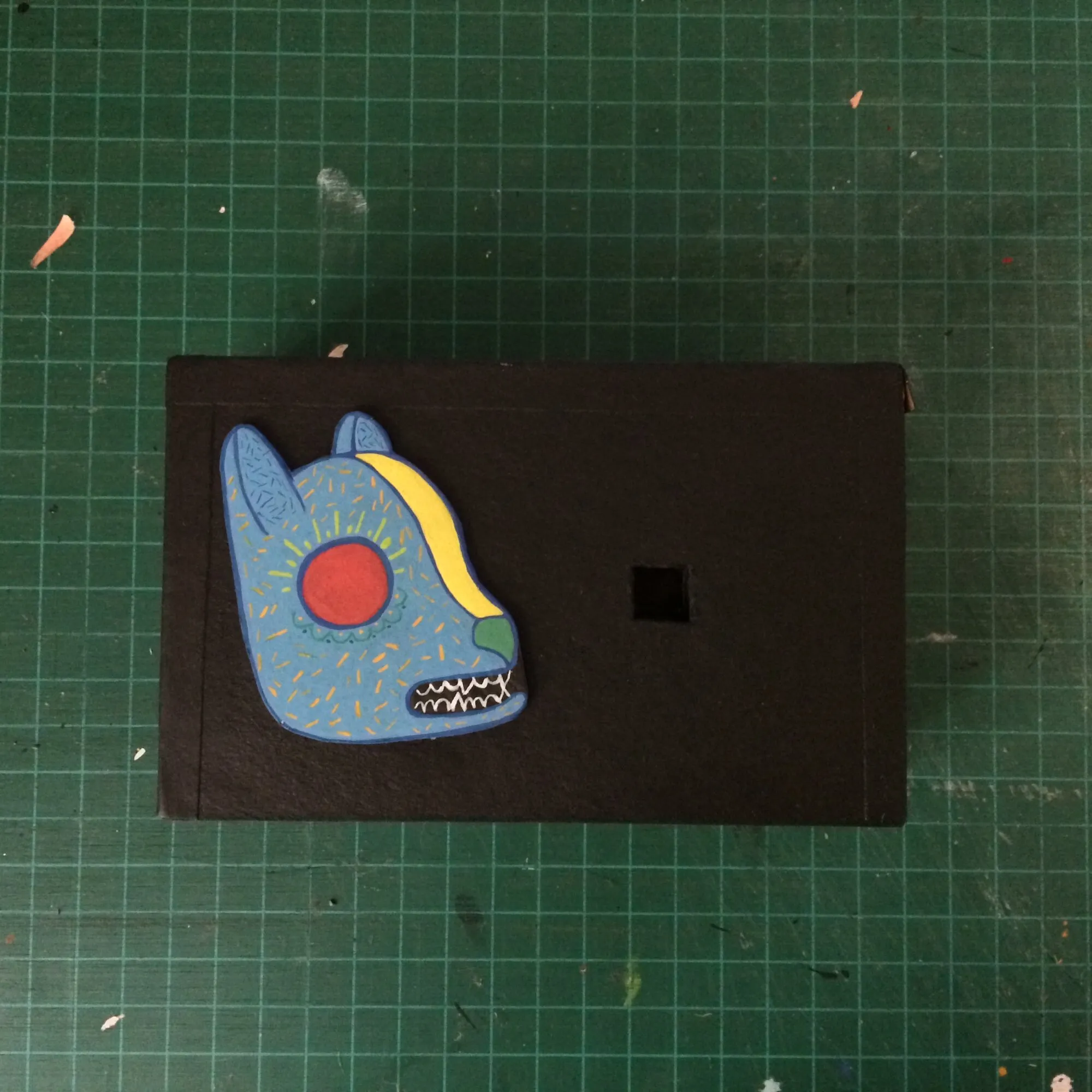 Cara trasera de la cámara con el alebrije azul de ojo rojo